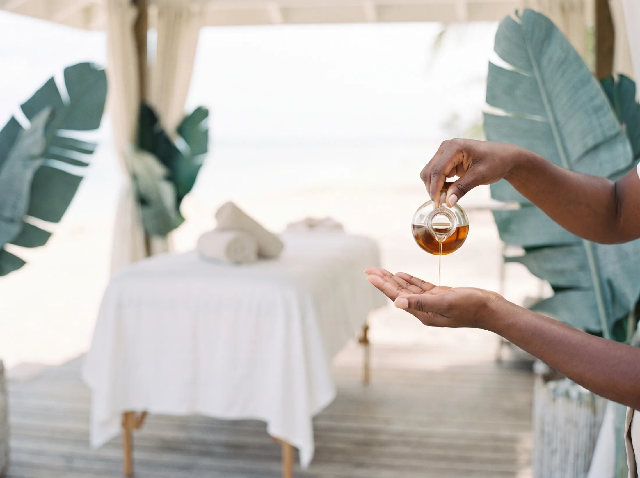 Mains d'un praticien versant de l'huile de massage tiède